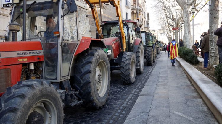 Els tractors en filera a la Rambla de Figueres durant la vaga del 21 de febrer del 2019 amb un vianant amb una estelada a l'esquena. ACN