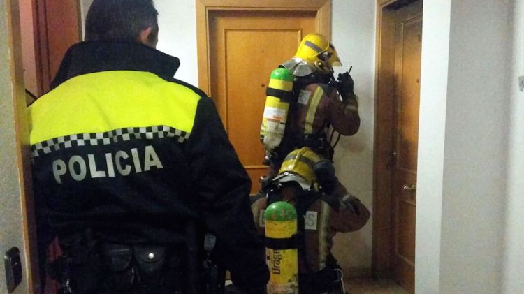 Dos bombers i un policia a la porta d'entrada del pis incendiat © ACN
