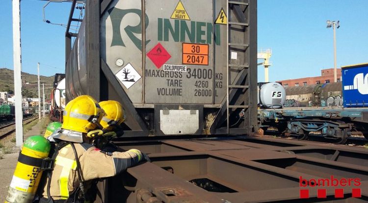 Dos efectius dels Bombers treballant per aturar la fuita de producte tòxic d'un tren de mercaderies perilloses