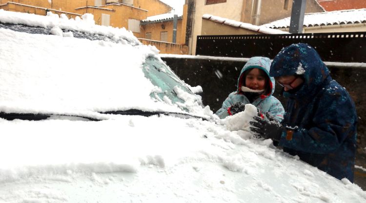 Nens jugant amb la neu que ha caigut damunt d'un cotxe a Maçanet de la Selva. ACN
