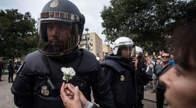 Una dona ofereix una flor a un membre de la policia espanyola al centre municipal d'ocupació de Sant Narcís a Girona. Carles Palacio/ACN
