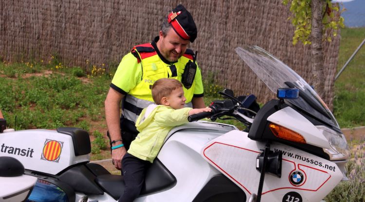 Un infant damunt de la moto dels Mossos i el coordinador de mobilitat segura, Joan López. ACN