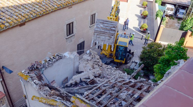 L'excavadora enderrocant l'habitatge adossat a la muralla de Llagostera aquet matí. ACN