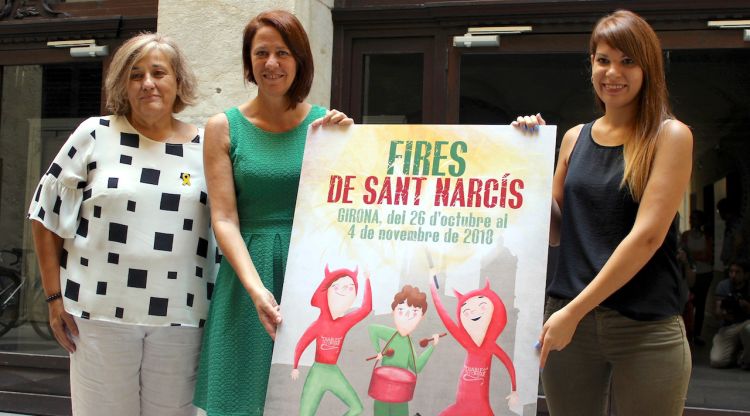 La regidora Eva Palau, l'alcaldessa Marta Madrenas i la dissenyadora Cristina Culubret, amb el cartell de les Fires de Sant Narcís
