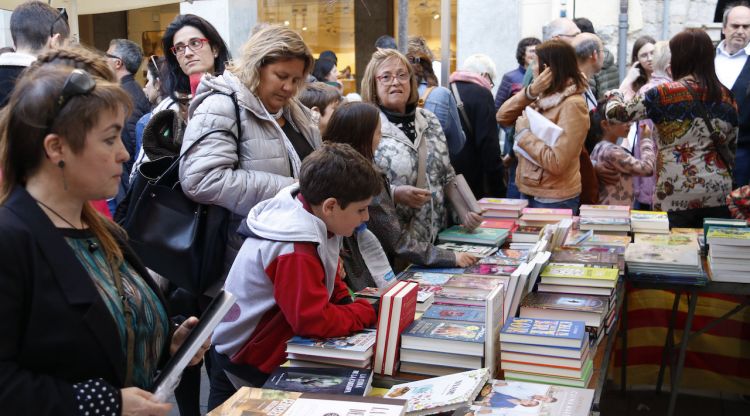 Alguns clients mirant llibres en una parada de la rambla de la Llibertat de Girona durant la diada de Sant Jordi. ACN