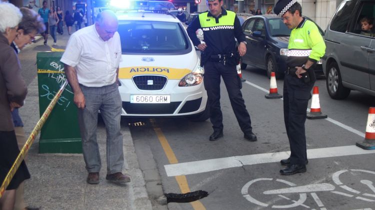 Agents de la Policia Municipal de Girona inspeccionen el forat mentre un grup de curiosos també l'observen © ACN