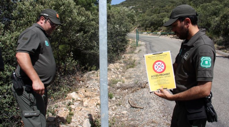 Dos Agents Rurals a punt de col·locar un cartell que indica que està prohibit accedir a la serra del Montsec. ACN