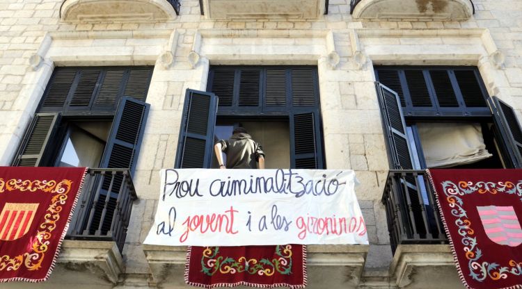 Pancarta denunciant la "criminalització" del jovent penjada a la façana de l'Ajuntament de Girona. ACN