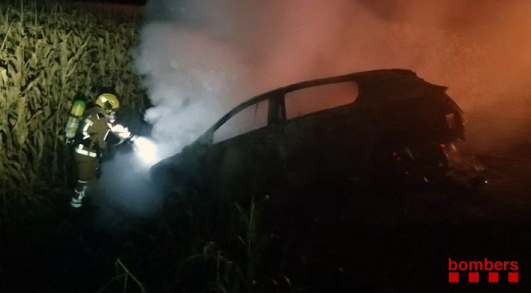 Un bomber apagant l'incendi que s'ha generat en un vehicle