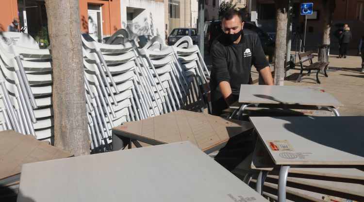 El propietari del bar El Caixer de Vilobí, Jordi López, recollint les cadires i taules. ACN