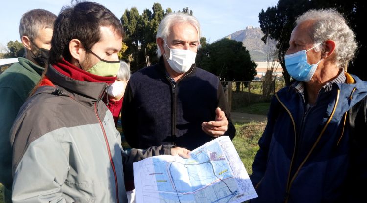 El representants de les entitats naturalistes i el d'Unió de Pagesos, mirant el plànol de les dues alternatives que es proposen per a la variant de Torroella (arxiu). ACN