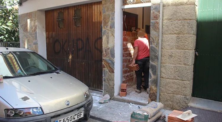 Els veïns tapiant l'entrada de l'habitatge després que els ocupes van ser detinguts. viladeroses.cat
