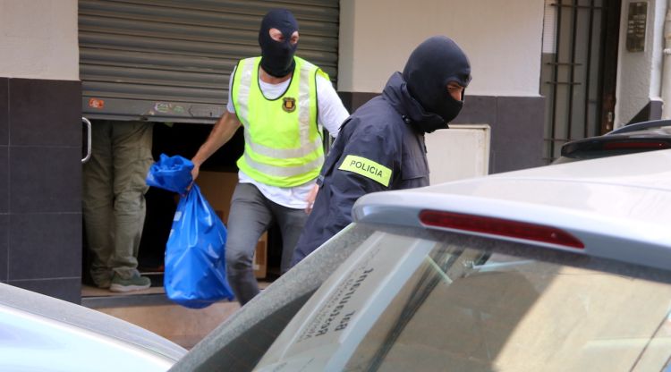 Agents dels Mossos d'Esquadra sortint carregats de bosses d'un bar de Gavà. ACN