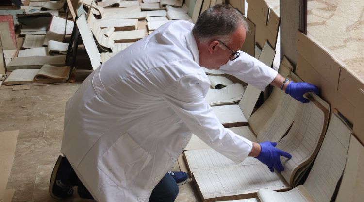 Un treballador de l'Arxiu Històric de Girona estèn alguns documents afectats per la fuita d'aigua. ACN