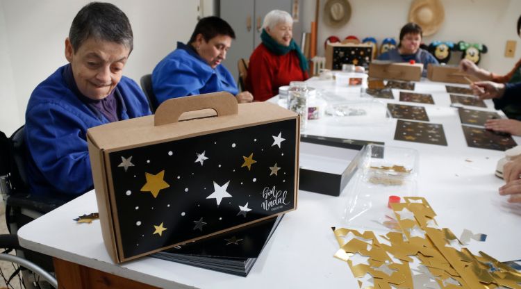 Usuaris de la Fundació MAP durant el taller de fer caixes de panera de Nadal. ACN