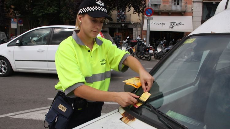 Una agent cívic de Girona posant un avís al parabrisa d'un vehicle que està mal estacionat © ACN