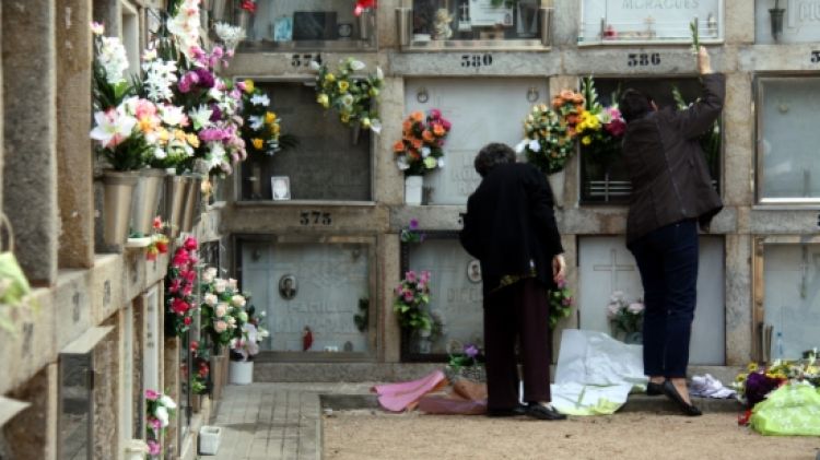 Diverses persones col·locant flors al cementiri de Girona © Nerea Guisasola